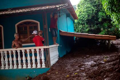 Una familia del pueblo Parque da Cachoeira observa los daños que produjo el barro en su vivienda