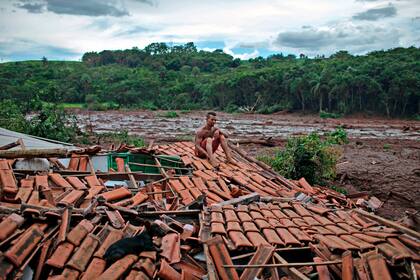 Emerson dos Santos, de 30 años, sentado sobre el techo de su vivienda familiar destruida por el colapso del dique de la mina de Vale S.A.