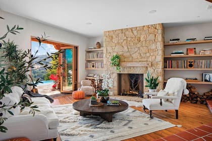 La cálida sala de estar tiene un hogar revestido con piedra natural, pisos de madera y espectaculares vistas a la montaña.
