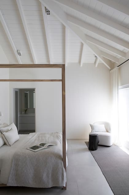 La cama con baldaquino en madera maciza (Estudio Mariana Flombaum) se acompañó de textiles de lino e hilo de algodón tejido (Gutiérrez Deco).