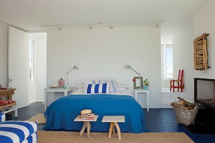 La cama vestida con una combinación de azul y blanco está escoltada por dos mesitas con tapa de mármol de Carrara (Laura O.) de diferente tamaño con sendas lámparas 'Tolomeo'.