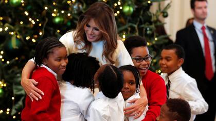 Varios ni?os abrazan a Melania Trump luego de preparar los adornos navide?os para la Casa Blanca