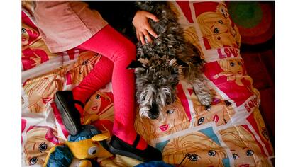 Luna juega con su perro Stark en su colcha con tema de Barbie en su casa en Santiago, Chile