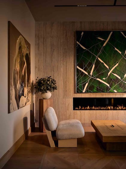 La chimenea, integrada discretamente sobre una pared de piedra, realza el aspecto acogedor del ambiente.