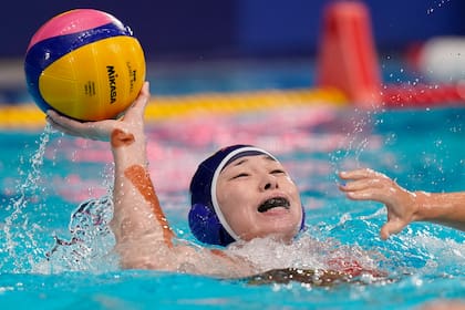 La china Xinyan Wang pasa el balón mientras se aleja de un defensor durante un partido de waterpolo femenino de la ronda preliminar contra Estados Unidos en los Juegos Olímpicos de Verano de 2020, el lunes 26 de julio de 2021, en Tokio, Japón.
