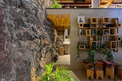 La circulación del living al toilet muestra todos los materiales presentes en la vivienda: roca natural, microcemento alisado y madera, en este caso paraíso.