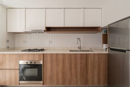 La cocina combina funcionalidad y calidez: muebles en madera y blanco, mesada de granito y detalles que integran diseño contemporáneo con practicidad.