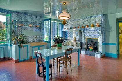 La cocina con chimenea, en azulejos azules Rouen, contrasta con los tonos cálidos del estar y el amarillo del comedor.