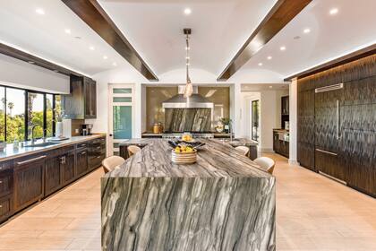 La cocina, con muebles de madera oscura y una enorme isla de mármol.