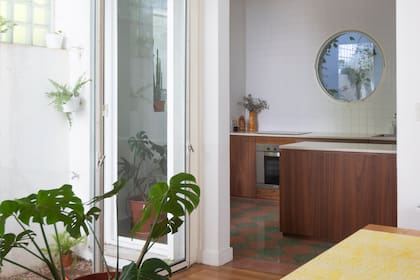 La cocina, con piso de baldosas de granito originales en damero rosa y verde oscuro, se conecta con el estar principal y el patio delantero.