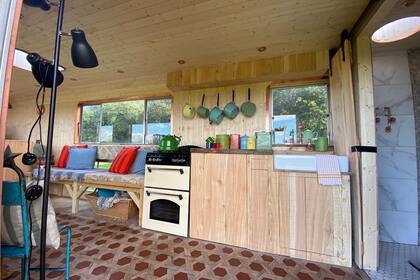 La cocina con un sillón al lado que permite guardar debajo diferentes cosas en canastos