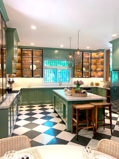 La cocina de Gaby López Monzón: muebles verdes, vitrinas iluminadas y una isla central que convierte el corazón de la casa en un espacio cálido, funcional y lleno de carácter.
