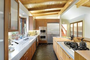 La cocina está hecha con muebles de madera y marmol blanco.