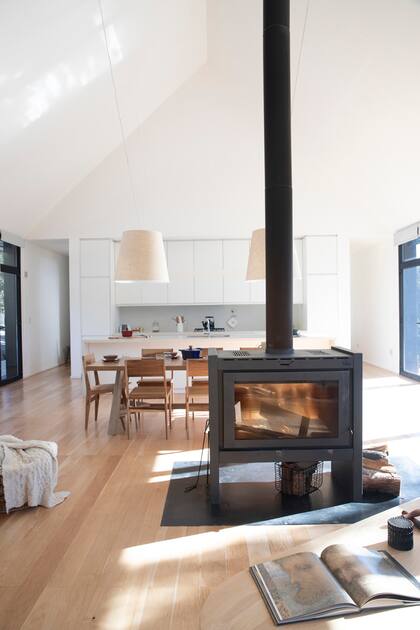 La cocina integrada sigue el concepto de claridad y continuidad con una gran barra (Di Gallo Marmolería) y muebles (Estudio Tulio Rossini) que ocultan incluso la heladera.