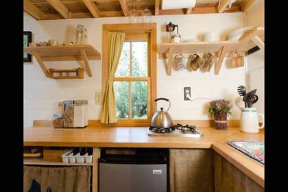 La cocina mantiene acabados de madera y suma plantas que llenan de vida el ambiente. En el fregadero de la cocina se añadió una colorida cerámica que rompe con la decoración rústica.