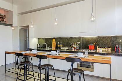 Este sector se resolvió con muebles con frente laqueado blanco, combinados con mesada y alzada en contrastante mármol negro.