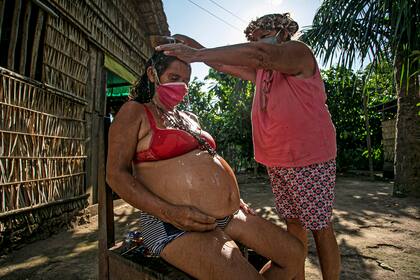 La comadrona Paje Suzete de la tribu Kumaruara baña a su hija embarazada antes del parto de su bebé en su casa junto al río Tapajos del municipio de Santarem en el oeste del estado de Pará, Brasil, el 10 de julio de 2020, en medio de la pandemia de coronavirus