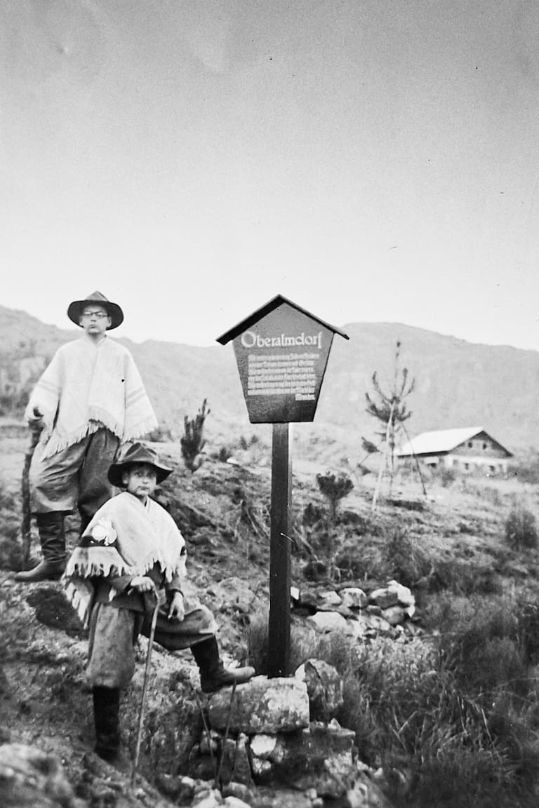 Klaus y Helmut Cabjolsky (hijo) junto al cartel que denominaba al lugar como "Oberalmdorf" nombre que cambiaron después del año 1937