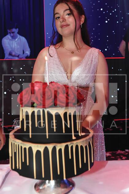 La cumpleañera con la torta de chocolate, decorada con rosas.