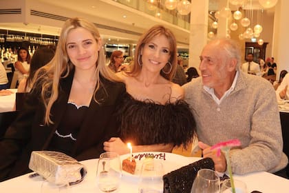 La cumpleañera,
rodeada por su
hija, “Tosky”, y por
su pareja, Gustavo
Yankelevich, a
punto de soplar
la velita que le
pusieron a su
torta.
