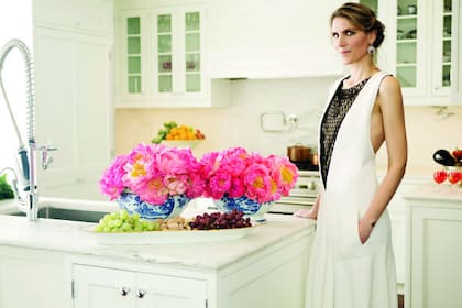 La diseñadora y creadora de la marca Candela en la cocina de su casa con un traje de Céline y aros de brillantes estilo art déco