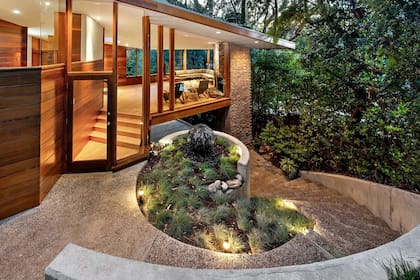 La entrada principal y el palier destacan por el uso de madera y vidrio en el diseño arquitectónico