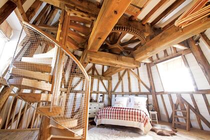 La escalera caracol con peldaños de madera maciza lleva a un tercer nivel exclusivamente destinado al cuarto de baño.