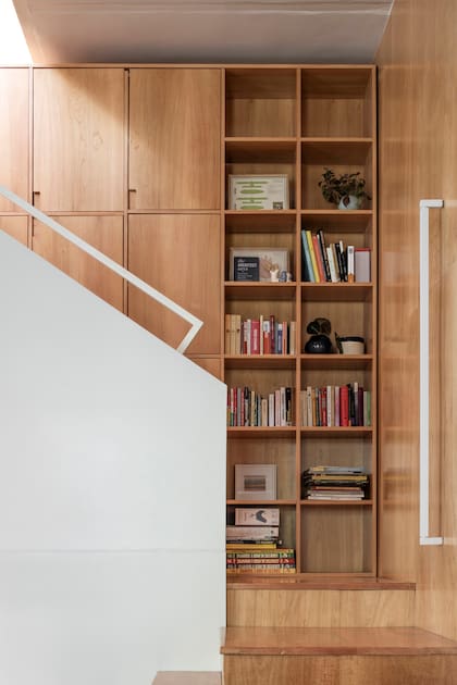 La escalera es de guatambú macizo tonalizado y la biblioteca se enchapó en la misma madera. El aplique lineal (Huup) tiene un diseño similar al de la baranda.