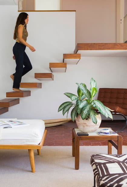 La escalera flotante fue uno de los detalles que convencieron a Maite de comprar la casa. Banquetas sin respaldo tapizadas con telas africanas que compró su madre en Nueva York.