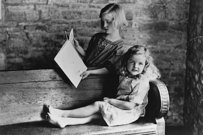 La escritora inglesa Jessica Mitford (sentada), a los seis años, leyendo con su hermana Unity, de nueve años, en el jardín de Asthall Manor, su casa en Oxfordshire, 1923. (Foto de Evening Standard/Getty Images) (Foto de © Hulton-Deutsch Collection/CORBIS/Corbis via Getty Images)