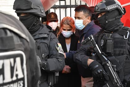 La ex presidenta interina de Bolivia, Jeannine Anez (C), es escoltada por miembros de la policía de la Fuerza Especial contra el Crimen (FELCC) luego de ser arrestada en La Paz
