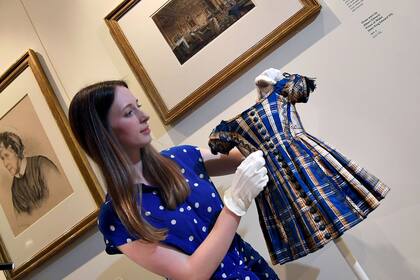Una empleada posa con uno de los vestidos infantiles de la Reina Victoria
