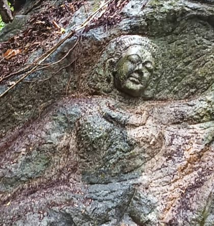 La figura de la escultura es de una persona con cabello largo sosteniendo una rama de árbol sobre su cabeza