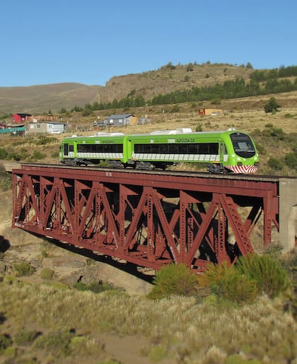 La formación ferroviaria atraviesa el pintoresco puente rojo sobre el río Ñirihuau
