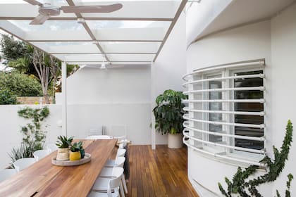 La galería de la casa abre el interior al jardín. El piso (Vier Abinet) y la mesa (La Base Studio) están revestidos en lapacho. Sillas ‘Unique’ (Vivre).