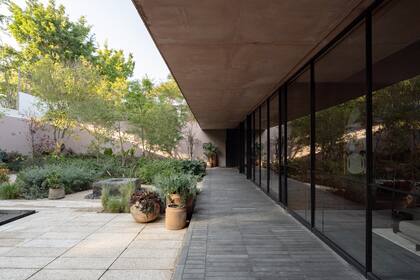 La galería, junto a una pileta que refleja el paisaje, incorpora una fuente geométrica que añade movimiento visual, mientras que los pisos circulares combinan piedra local y concreto prefabricado, organizando el espacio de manera fluida.