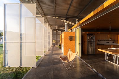 La galería semicubierta funciona como una segunda piel: puede cerrarse por completo y ofrece un espacio que combina parrilla, mesada y un rincón de estudio, siempre resguardado del clima y las miradas.