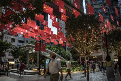La gente camina bajo banderas de China y la Región Administrativa Especial de Hong Kong, en Queen's Road en Honk Kong