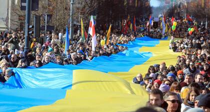 La gente camina con una bandera ucraniana gigante para protestar contra la invasión rusa de Ucrania en Vilna, Lituania, el 11 de marzo de 2022.