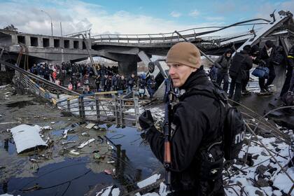 La gente camina debajo de un puente destruido mientras huía de Irpin, en las afueras de Kiev, Ucrania
