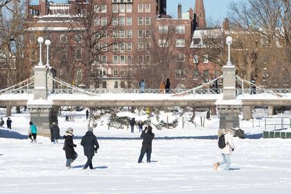 La gente camina en la laguna congelada y cubierta de nieve en Boston Common después de la tormenta de invierno Kenan el 30 de enero de 2022 en Boston, Massachusetts.
