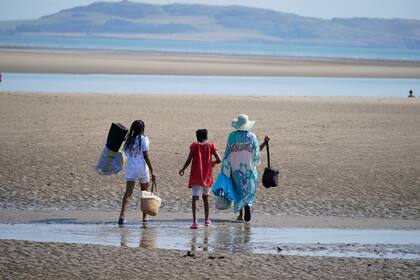 La gente camina en la playa de Malahide, cerca de Dublín, Irlanda, el lunes 18 de julio de 2022.