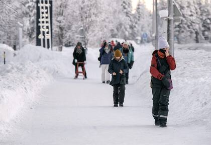 La gente camina en un paisaje nevado en la ciudad de Äkäslompolo, en el municipio de Kolari en la Laponia finlandesa el 4 de enero de 2024, durante condiciones de congelación extrema que persistirán durante toda la semana no solo en Laponia sino en toda Finlandia.
