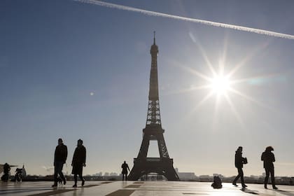 La gente camina frente a la Torre Eiffel, en la plaza Trocadero de París, hoy, durante el segundo confinamiento de Francia para contener el coronavirus