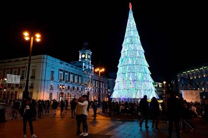 La gente camina frente a las luces navideñas en las calles de Madrid