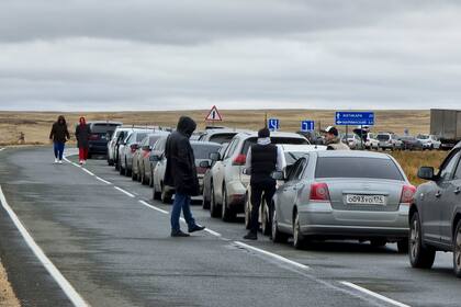 La gente camina junto a sus automóviles haciendo fila para cruzar la frontera de Rusia con Kazajistán.