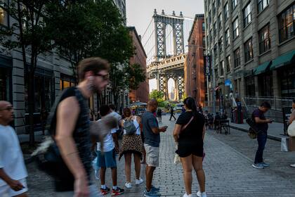 La gente camina por las calles de la ciudad a la vista del puente de Manhattan en una tarde sofocante 