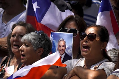La gente canta el Himno Nacional frente al exCongreso en Santiago, mientras aguarda para despedir al expresidente Sebastián Piñera (AP Photo/Matias Basualdo)