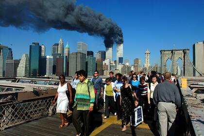 La gente cruza el Puente de Brooklyn alejándose de las torres de World Trade en llamas antes de su derrumbe