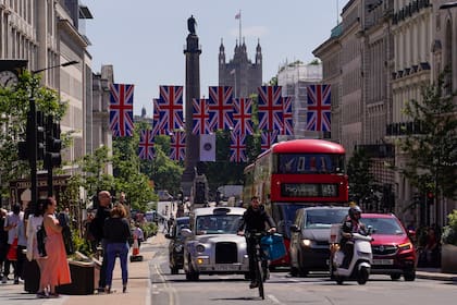 La gente cruza la calle en Piccadilly Circus mientras la calle está decorada con banderas de la Unión, en Londres, el viernes 27 de mayo de 2022